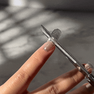 Step four of applying EyeCandys Gel Nail Stickers: cutting excess sticker for a perfect fit, ensuring a polished and long-lasting gel manicure