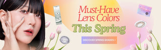 Banner is showing 2 scattered color contact lenses box. Each side of the banner has decorative graphics of tulips to show spring aesthetics. Female model wearing brown colored contact lenses can be seen at the left side of the banner. Text displaying 'Must-Have Lens Colors This Spring' is seen at the center part of the banner.