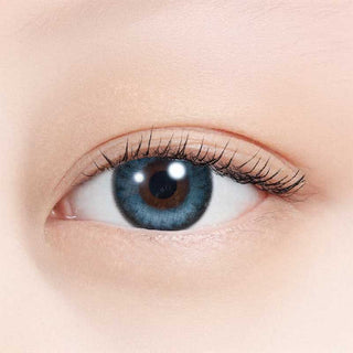 A close-up of a human eye with N's Collection Umi Blue (10pk) colored contacts shows long dark lashes, light skin, and an open eye highlighting the detailed iris and reflections on the daily disposable myopia lens from N's Collection.