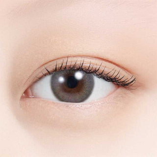 A close-up of a brown eye with long lashes, natural makeup, and smooth light skin wearing N's Collection Zunda Mochi Green (10pk) daily disposable colored contacts by N's Collection.