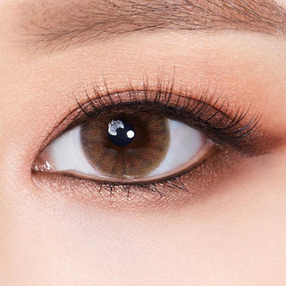 Macro shot of an eye wearing the Olola Amuse Brown (KR) prescription colour contact lens, showing the multi-colored detail and natural effect on dark brown eyes.