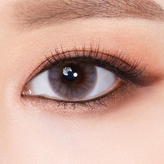 Macro shot of an eye wearing the Olola Amuse Grey (KR) prescription colour contact lens, showing the multi-colored detail and natural effect on dark brown eyes.