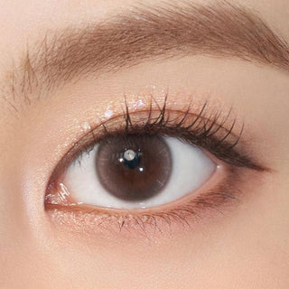 Close-up shot of model's eye adorned with Chuu Aube Pie Moon Brown color contact lenses with prescription, complemented by minimalist eye makeup, showing the brightening and enlarging effect of the circle contact lens on dark brown eyes.