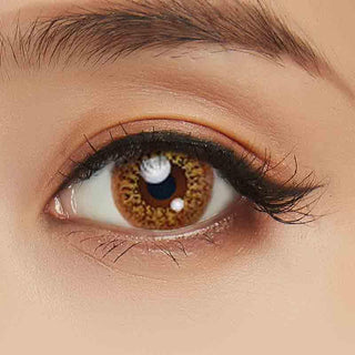 Close-up shot of a model eye wearing Lacelle Colors Vivid Gold colored contact lens in one eye that is naturally dark-brown with natural eye make up and long lashes