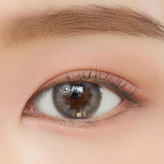 Close-up shot of model's eye adorned with Chuu Cloud Pudding Grey (10pk) color contact lenses with prescription, complemented by minimalist eye makeup, showing the brightening and enlarging effect of the circle contact lens on dark brown eyes.