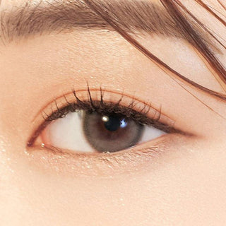 Close-up shot of model's eye adorned with Gemhour Everyday Essentials Grey color contact lenses with prescription, complemented by minimalist eye makeup, showing the brightening and enlarging effect of the circle contact lens on dark brown eyes.