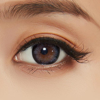 A close-up image capturing the intricacies of the model's eye, accentuated by the Pink Label Blossom Grey contact lens and accompanied by peach-colored eyeshadow.