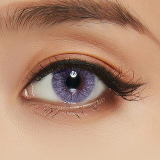 Macro shot of purple contacts with intricate spiral dot design, worn on a dark brown Asian eye