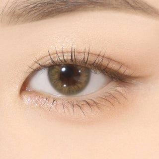 Close-up shot of model's eye adorned with Gemhour Hestia Olive color contact lenses with prescription, complemented by minimalist eye makeup, showing the brightening and enlarging effect of the circle contact lens on dark brown eyes.