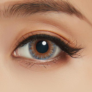 Close-up shot of model's eye adorned with Lilmoon Monthly Water Water Blue-Grey (Prescription) color contact lenses with prescription, complemented by minimalist eye makeup, showing the brightening and enlarging effect of the circle contact lens on dark brown eyes.
