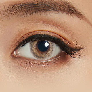 Close-up shot of model's eye adorned with Lilmoon Monthly Cream Beige (Prescription) color contact lenses with prescription, complemented by minimalist eye makeup, showing the brightening and enlarging effect of the circle contact lens on dark brown eyes.