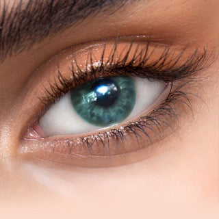 Close-up shot of a model eye wearing Sugarlook Green colored contact lens in one eye that is naturally dark-brown with natural eye make up