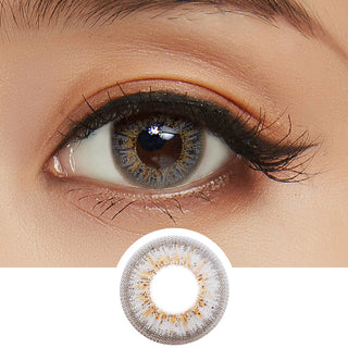 Close-up shot of model's eye adorned with Pink Label Obsession Grey color contact lenses with prescription, complemented by clean eye makeup, showing the brightening and enlarging effect of the circle contact lens on dark brown eyes, above a cutout of the contact lens pattern with limbal ring on a white background.