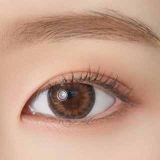 Close-up shot of model's eye adorned with Chuu Sunny Cookie Brown color contact lenses with prescription, complemented by minimalist eye makeup, showing the brightening and enlarging effect of the circle contact lens on dark brown eyes.