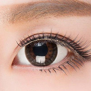 Close-up shot of a model eye wearing Lacelle Dazzle Ring Twinkling Bronze colored contact lens in one eye that is naturally dark-brown with natural eye make up and long lashes - EyeCandy's