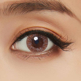 Close-up view of the model's eye featuring Birthday brown contact lens paired with peach eyeshadow