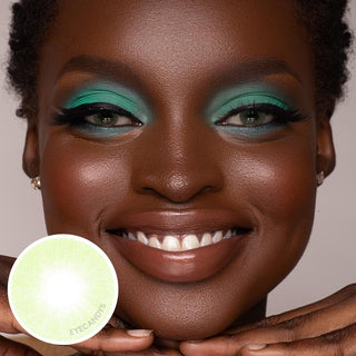 Model wearing EyeCandys Glossy Green contact lenses on black eyes with matching green makeup