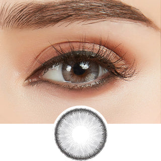 Macro shot of an eye wearing the desire mist grey colour contact lens, showing the light color detail and natural effect on dark brown eyes, with rose gold eye makeup, with a cutout detail of the same lens below