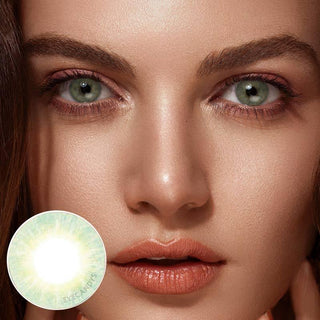 Close-up photo of a model with brown hair wearing Libre Green contact lenses, complemented by peach eyeshadow, highlighting their naturally dark eyes, with a detailed view focusing on the lenses. The image also includes a close-up of the contact lens.