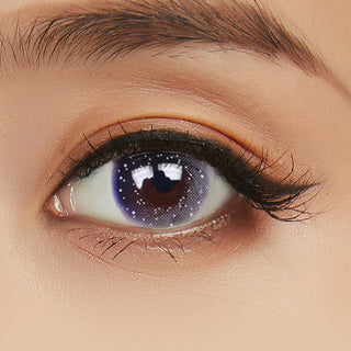 Close view of a Pink Label Galaxy Grey contact lens with a purple tint on a model's eye paired with peach eyeshadow