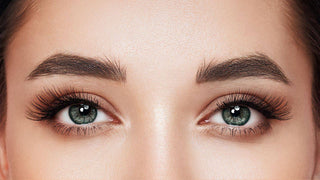 Clear green eyes framed by full dark eyelashes and neatly shaped eyebrows.