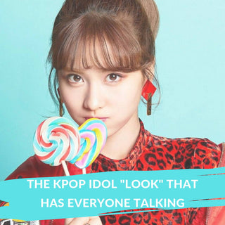 A woman holding swirl lollipops against a blue background, showcasing wide brown kpop idol eyes.