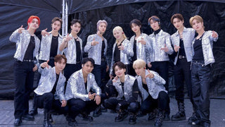 Members of K-pop group SEVENTEEN pose together in matching glittering silver jackets and black pants.