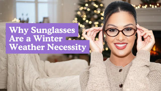 Smiling woman adjusting oval tortoiseshell glasses in a cozy room with a lit Christmas tree.