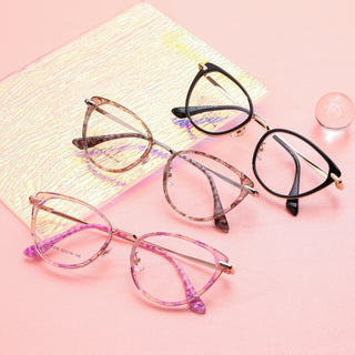 Various colors of the Aura cat-eye vintage eyeglass frames, in purple, pink tortoiseshell and black, available in blue light blocking lenses and readers, photographed on a pink background, from EyeCandys