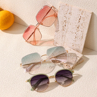 Three pairs of EyeCandys Bermuda Oversized Square Sunglasses are displayed on a textured surface with two orange balls in the background. Each pair boasts a unique frame: one with Glacier and Pink Swizzle colors, another featuring gradient green and pink lenses, and the third flaunting dark purple lenses wrapped in a gold frame.