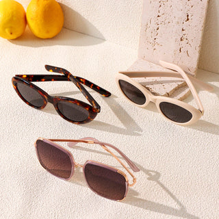 Various colors of the Boom Retro Cat Eye Sunglasses sunglasses frames, in Tortoiseshell, White, available in blue light blocking lenses and readers, photographed on a purple peach, from EyeCandys