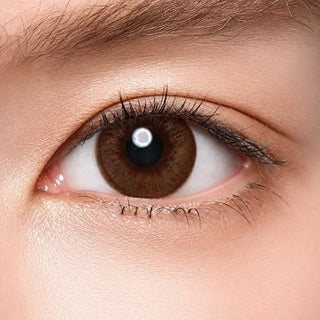 Model's eye wearing the Acuvue Sheer Allure color contact lens with light eye makeup, showing the widening effect of the circle lens on a dark iris.