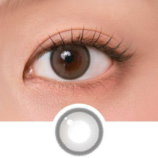 Close-up shot of model's eye adorned with Chuu Aery Rose Lucid Grey (10pk) daily color contact lenses with prescription, complemented by glittery eye makeup, showing the brightening and enlarging effect of the circle contact lens on dark brown eyes, above a cutout of the contact lens pattern with limbal ring on a white background.