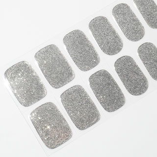 Angled image of semi-cured gel nail stickers in the design 'All That Glitters,' featuring a sparkling silver glitter finish for a dazzling and glamorous manicure