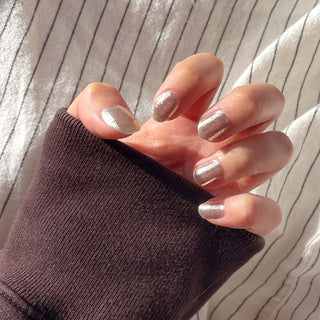 Model's hand showcasing EyeCandys All That Glitter Gel Nail Stickers. These white glitter stickers provide a dazzling, sparkling effect, offering a glossy and long-lasting finish for a chic and festive manicure.