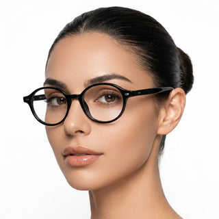 A woman with smooth, light brown skin and dark hair in a neat bun wears EyeCandys Chase Round Oval glasses, gazing slightly to the side against a plain white background.