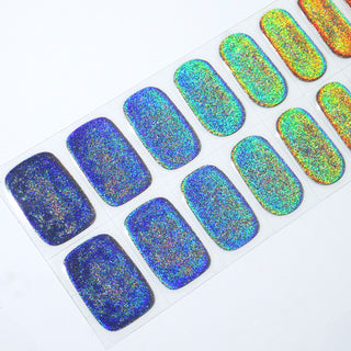 Angled image of semi-cured gel nail stickers in the design 'Cosmic,' featuring a gradient of blue glitter color ranging from deep blue to golden orange, perfect for a stylish manicure.