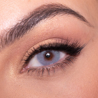 Macro shot of Date to be blue contact lens with intricate spokes design, modelled on a dark brown eye with natural eye makeup