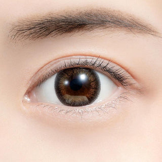Close-up shot of model's eye adorned with Feliamo 1-Day Tulle Brown (10pk) color contact lenses with prescription, complemented by minimalist eye makeup, showing the brightening and enlarging effect of the circle contact lens on dark brown eyes.