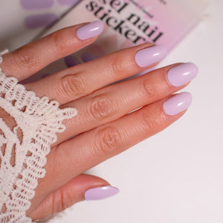 Model's hand showcasing EyeCandys French Lavender Gel Nail Stickers. These soft lavender-colored stickers offer a delicate, elegant look with a glossy finish, providing a long-lasting, chip-free manicure for a sophisticated and fresh touch to your nails.