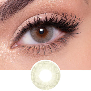 Glossy Ivory light beige colour contact lens worn on a dark eye paired with pearly peach eye makeup, above the lens design.