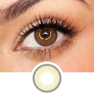 Pink Label Honey Donut Brown color contact lens on top of a dark eye paired with subtle eye makeup and curled wispy eyelashes, above the contact lens design.
