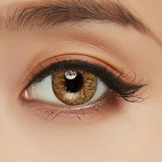 A close-up of a model's eye showcasing the Soony Brown contact lens designed for astigmatism, accompanied by peach eyeshadow.