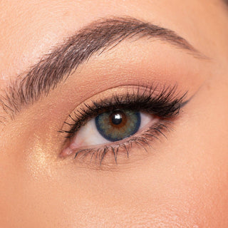Close-up shot of a model wearing EyeCandys Isla Blue Grotto colored contact lens in one eye that is naturally dark-brown