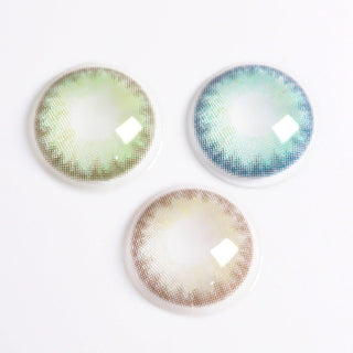 Three colored contact lenses are arranged on a white background. These non-prescription contact lenses display intricate patterns and come in green, blue, and brown shades. The lenses feature a gradient design, fading from the outer edge towards the center, with EyeCandys Isla Emerald Green by EyeCandys highlighting the collection.