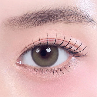 Close-up shot of model's eye adorned with Gemhour Khione 1-Day Olive (10pk) color contact lenses with prescription, complemented by minimalist eye makeup, showing the brightening and enlarging effect of the circle contact lens on dark brown eyes.