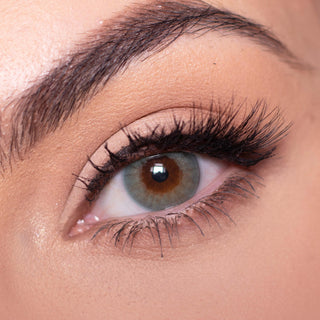 Close-up shot of a model with natural dark eyes wearing Libre Green colored contact lenses, complemented by natural eye make up. Close-up image showcases the model's eyes adorned with the same green contact lenses.