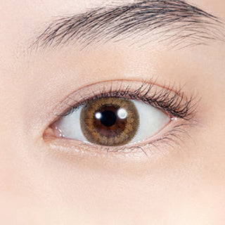 Close-up shot of model's eye adorned with Lilmoon Monthly Skin Beige (Prescription) color contact lenses with prescription, complemented by minimalist eye makeup, showing the brightening and enlarging effect of the circle contact lens on dark brown eyes.