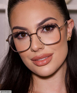 Model with black hair and natural simple make up look wearing Mystic Oversized Square vintage-inspired prescription eyeglasses, available in blue light blocking lenses and in readers with magnification, from EyeCandys. Pictured is the Smoke Crystal (silver-grey) color.
