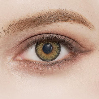 A close-up of a hazel eye with a brown and green iris, enhanced by NEO Vision Cosmo Green lenses from NEO Vision, with a subtly defined eyebrow and natural makeup on the eyelid and surrounding skin.